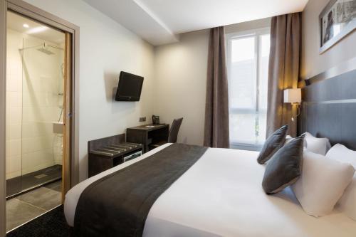ein Hotelzimmer mit einem großen Bett und einem Bad in der Unterkunft Hotel Paris Italie in Paris