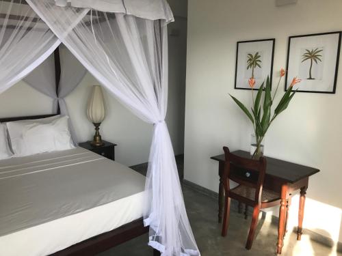 Lara's place في يوناواتونا: غرفة نوم بسرير مظلة وطاولة مع كرسي