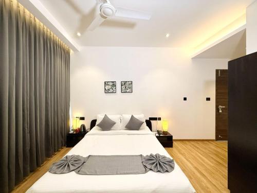 a bedroom with a large white bed with gray pillows at The Residence by Chakolas Pavilion in Cochin