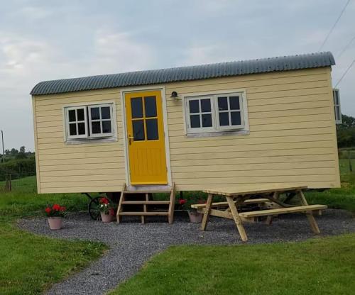 a large yellow tiny house with a yellow door at Abbeyview House B&B and Glamping in Abbeyshrule