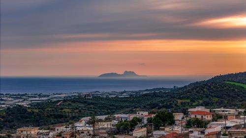 a view of a city and the ocean at sunset at Thea Villa in Kokkinos Pirgos