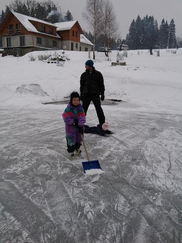 a man and a little girl on the ice at Apartmány Kuřátko in Benecko