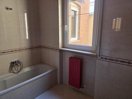 a bathroom with a tub and a window and a red radiator at House raffy in San Severo