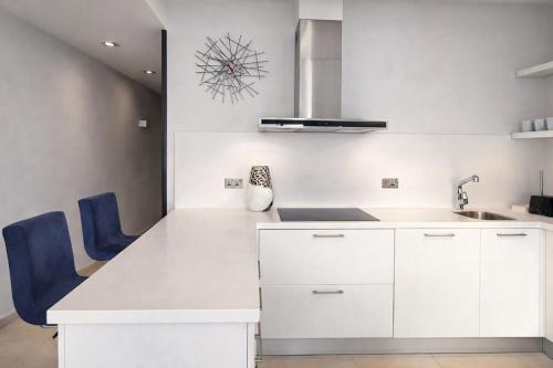 a white kitchen with white cabinets and blue chairs at Seafront-Top Location-Close To Shops & Restaurants in St. Julianʼs