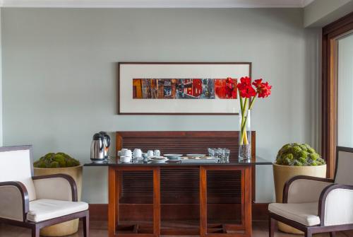 a dining room with a table with a vase of red flowers at Hotel Casa Higueras in Valparaíso