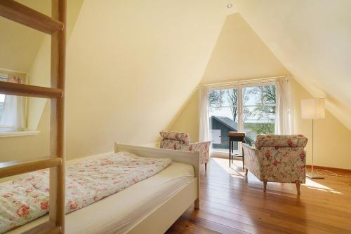 a bedroom with a bed and two chairs and a window at Haus Bei Der Kirche in Oland