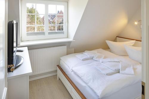 a white bed in a room with a window at Auster Holte Hüüs in List