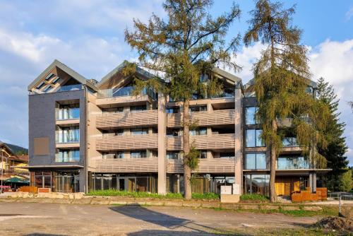 an apartment building with a tree in front of it at Mountain Apartment No 209-CORSO Harrachov, High Speed WI-FI, Ambilight smart TV, Netflix, YouTube, FREE parking, private SEJF, PRIVATE bike storage, HARRACHOVCARD in Harrachov