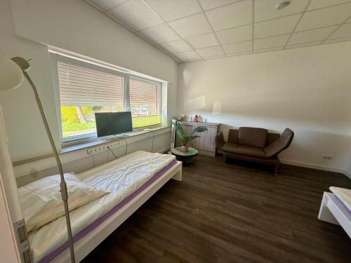 a room with a bed and a chair and a window at HörneNest Balje - Ferienwohnung zwischen Elbe & Oste in Balje