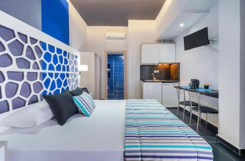 a bedroom with a large white bed and a kitchen at Fresh Mare Apartments in Limenaria