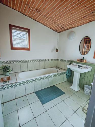 a bathroom with a tub and a sink at Mienru House Self Catering Cottage in Riviersonderend
