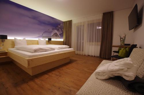 a bedroom with a bed with a painting on the wall at Hotel Zerres in Partenen