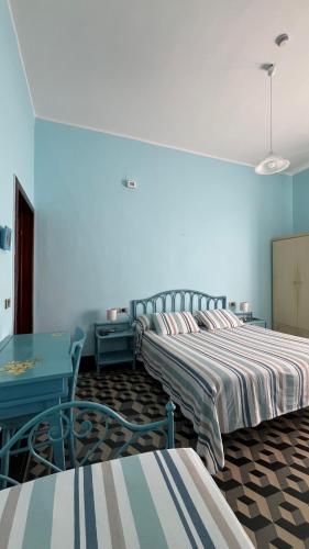 two beds in a room with blue walls and a table at Albergo Pensione Bartoli in Castiglioncello