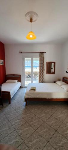 a bedroom with two beds and a large window at Plaka Apartments in Fournoi
