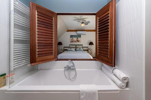 a bathroom with a tub and a bed in a room at Maison D'hôtes De Calzac Moulin - in Le Gorvello