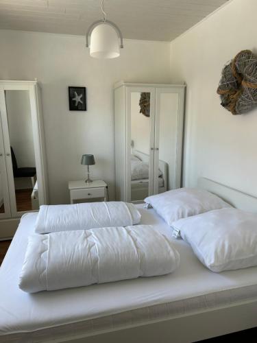 two white beds in a bedroom with two mirrors at Kleine Hafenperle in Varel