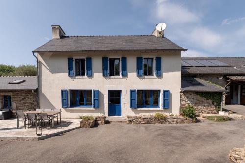a white house with blue windows and a table at Maison familiale 10 personnes in Bannalec