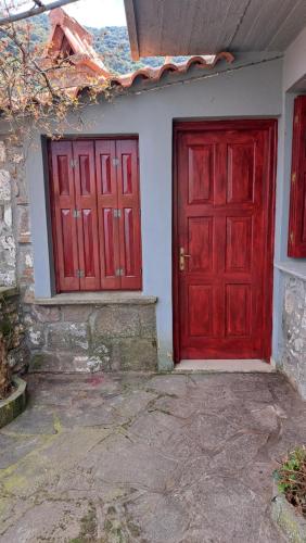 two red doors on the side of a house at Serafima's house Lesvos in Sykaminéa