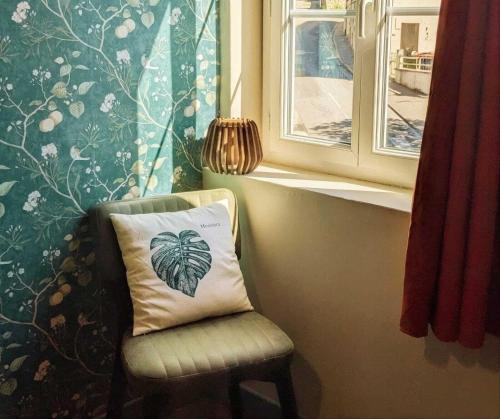 a pillow sitting on a chair next to a window at L'Authentique in Beaumont-le-Roger