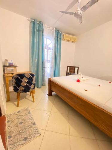 a bedroom with a bed and a chair and a window at Hello Rafiki Hotel Stone town in Ngambo