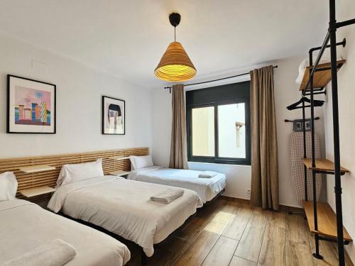 a room with two beds and a pendant light at Apartments Sant Lluis CENTER, 2 min walk from the sea in Lloret de Mar