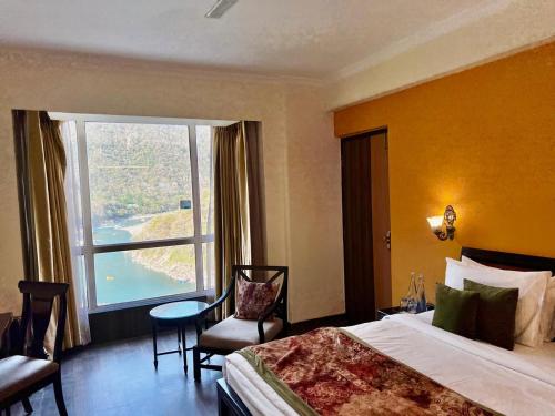 a hotel room with a bed and a large window at ALOHA ON SACRED GANGES 2BHK Premium Ganga View Apartment with Infinity Pool in Rishīkesh