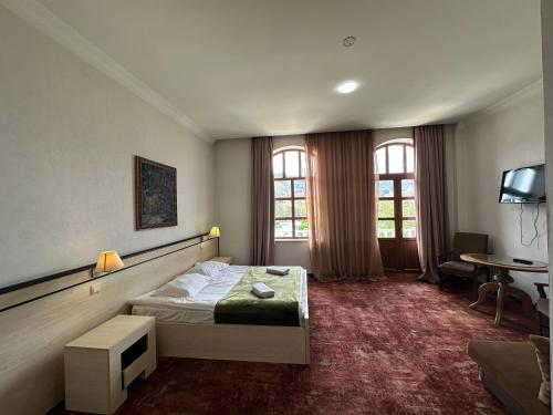 a bedroom with a bed and a desk and a tv at Hotel Cash in Tbilisi City