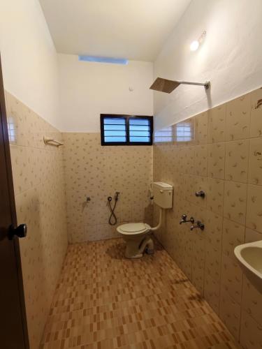 a bathroom with a toilet and a sink and a window at Aurena Stays Varkala in Varkala