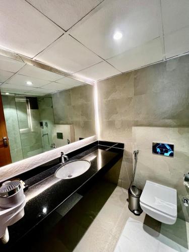 a bathroom with a sink and a mirror and a toilet at ALOHA ON SACRED GANGES 2BHK Premium Ganga View Apartment with Infinity Pool in Rishīkesh