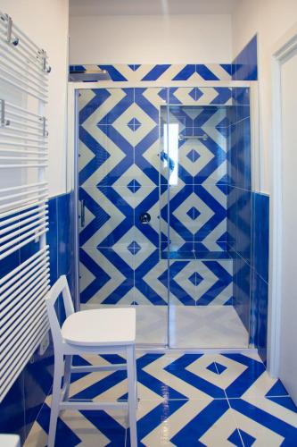 a blue and white bathroom with a chair and a shower at Isabel Luxury Suite in Ischia