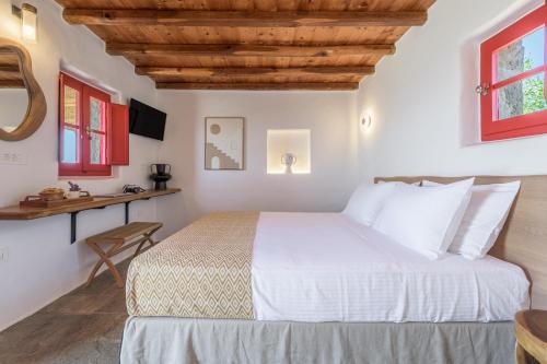 a bedroom with a white bed and a desk at Marketos Windmill House in Tripiti