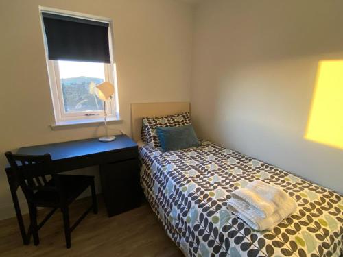 a bedroom with a bed with a desk and a window at Housegarth in Twatt