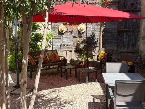 a patio with a red umbrella and chairs and tables at Le Clos d'Orange - Hotel & ville de Provence in Orange