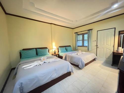 a bedroom with two beds with white sheets and blue pillows at Moonlit Garden Koh Chang in Ban Dan Kao