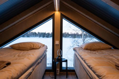 two beds in a room with a large window at Aurora Lake Lodges in Ranua