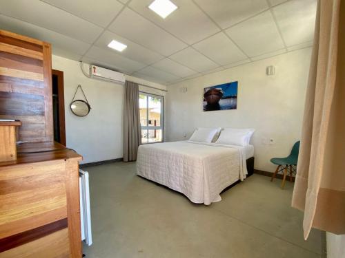 a bedroom with a white bed and a chair at CAMALEÃO Ecopousada Ltda in Linhares