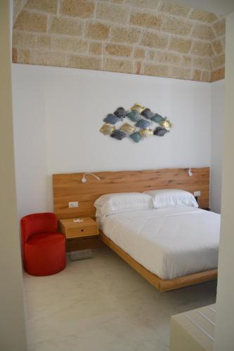 a bedroom with a bed and a red chair at DuOr Suite & Rooms in Polignano a Mare
