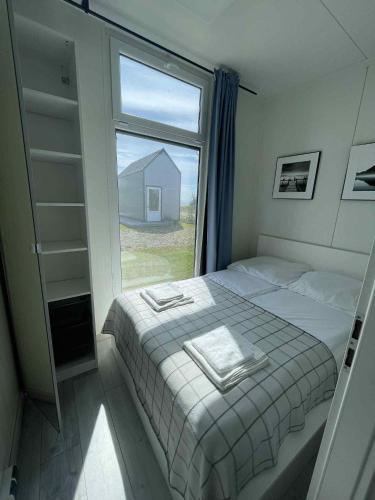 a bedroom with a bed and a large window at Surf Osada, komfortowe domki w kameralnej okolicy nad samym brzegiem Zatoki Puckiej in Swarzewo