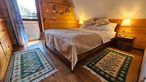 a bedroom with a bed and two rugs at Chatka Kudłatka in Wetlina
