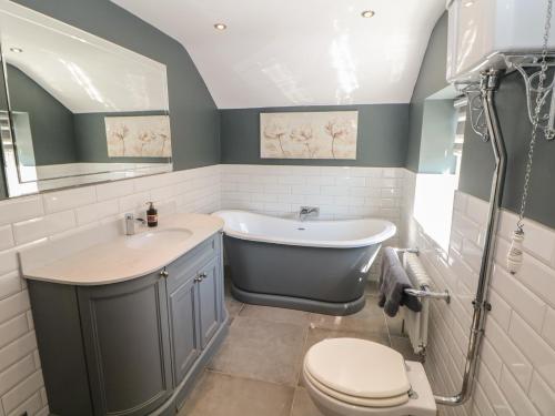 a bathroom with a tub and a sink and a toilet at Pine Cottage in Hathersage