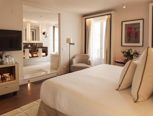 a white bedroom with a large bed and a chair at Hospes Puerta de Alcalá, a Member of Design Hotels in Madrid