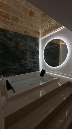 a bathroom with a bath tub with a round mirror at DuOr Suite & Rooms in Polignano a Mare