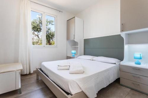 a white bedroom with a bed and a window at La Pineta Residence in Otranto