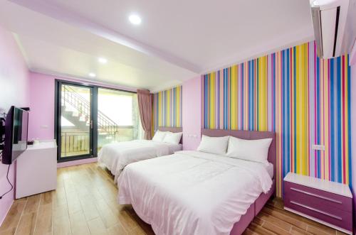 a bedroom with two beds and a colorful wall at 遇見龜山島 in Toucheng