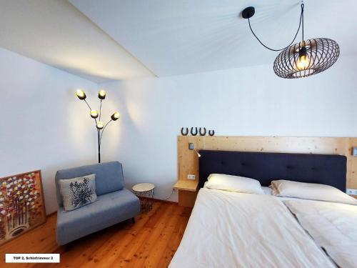 a bedroom with a bed and a blue chair at Bel Appartement Bad Kleinkirchheim in Bad Kleinkirchheim