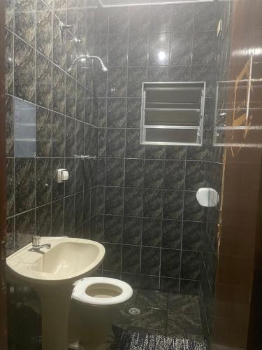 a black tiled bathroom with a toilet and a sink at Hotel e Pousada Porto Forte in São Paulo
