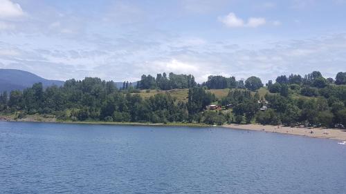 a body of water with a beach with people on it at Vientos de Chauquen in Panguipulli