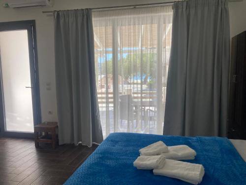 a bedroom with a blue bed with towels on it at Agioi Apostoloi apartments in Agioi Apostoli