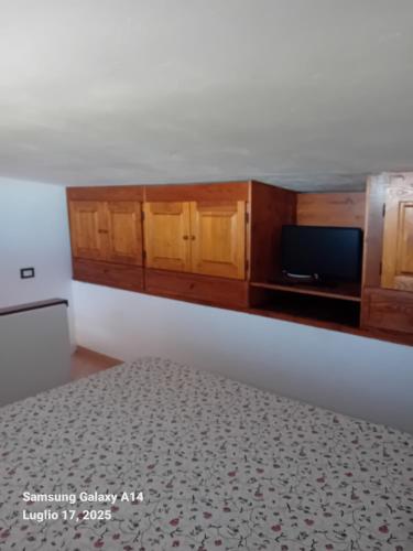 a room with a bed and wooden cabinets and a tv at Casa SILMAGA in La Maddalena