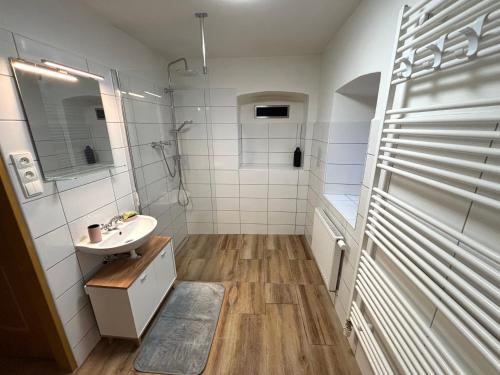 a white bathroom with a sink and a shower at BrezINNa - 200 let historie - moderní chalupa in Počátky